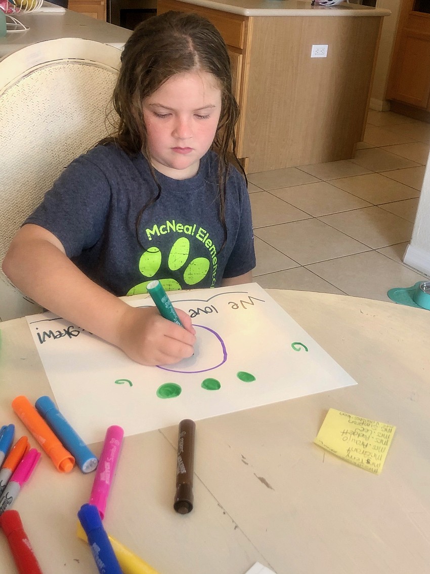 Ella Dyer, a third grader at Gilbert W. McNeal Elementary School, works on a sign for teachers and staff at the school. She later put the sign in the courtyard of the school so teachers can see it as they walk into the building.