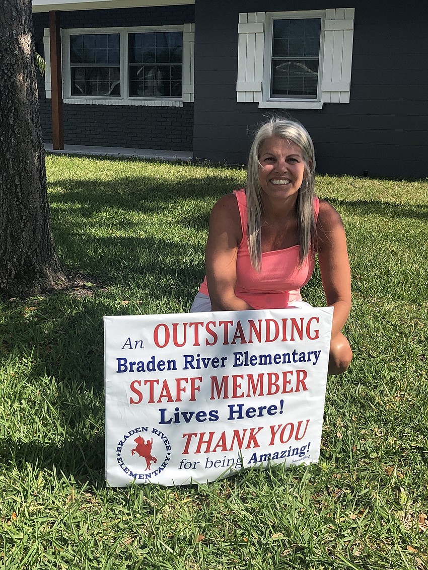 Brijet France, a fourth grade teacher at Braden River Elementary School, sits by the sign the school posted in her front yard for Teacher and Staff Appreciation Week.