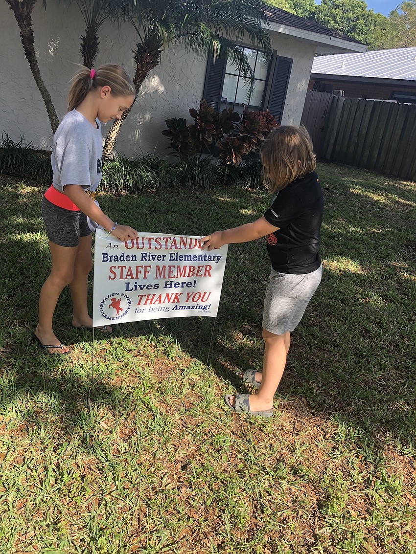 Kylee and Rylynn Francies, students at Braden River Elementary School, put a sign in the yard of a Braden River Elementary teacher.