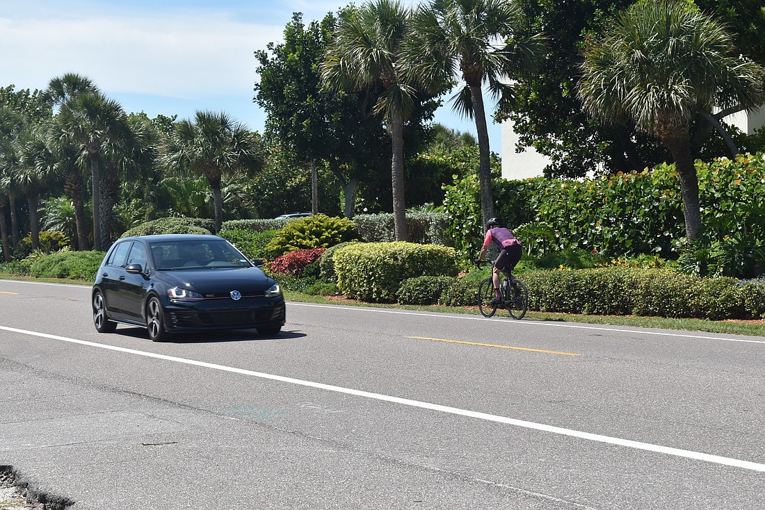 A cyclist rides with the flow of traffic in the bike lane.