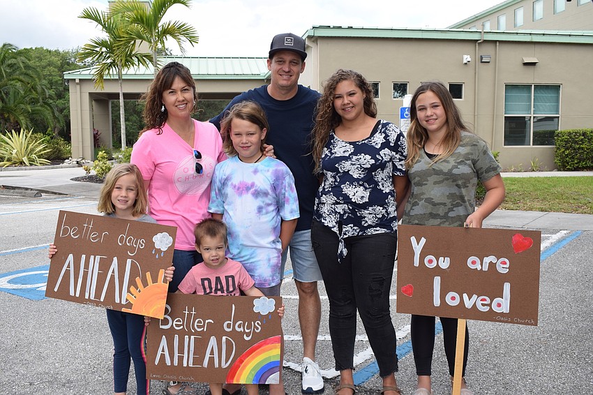 Eden, Kristin, Isaac, Levi, Steve, Elise and Myla Coad carry signs they displayed during an Oasis church parade to share messages of love and hope.