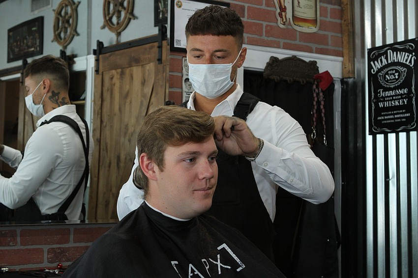 APX Barber Co. owner Andre Pergolese says the stores is busy, though haircuts are appointment only with one customer in the room.