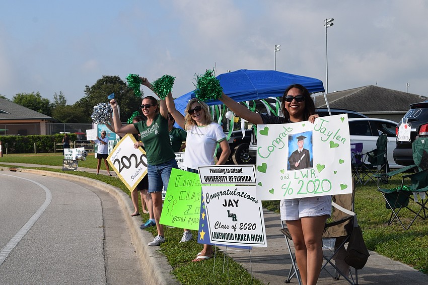 Jennifer Venuto, Jackie Breiner and Avelina Besse cheer as seniors drive by to get their caps and gowns. The parade was a surprise to honor seniors.