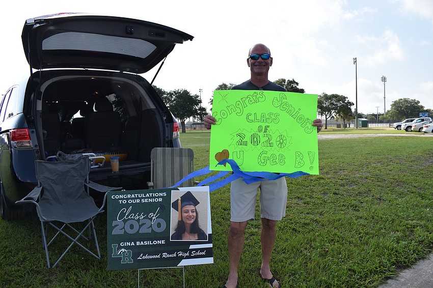 Dave Peters plays harmonica as seniors pass by in their cars. He was at the parade to cheer for his daughter Gina Basilone.