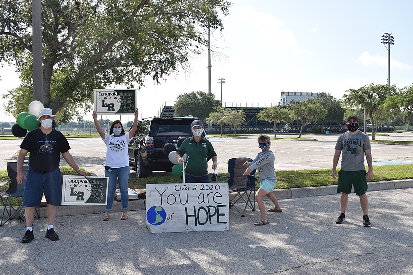 Lakewood Ranch High School teachers and staff members Charles Cook, Laura Anderson, Maggie Sharrer, Carol Lidey and Jeremy Schiller pass out yard signs to seniors.