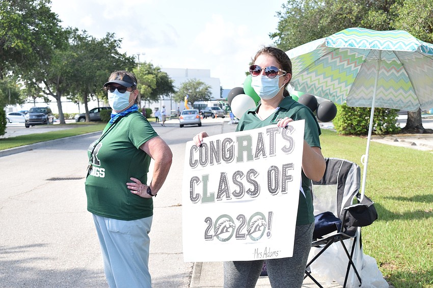 Language arts teacher Mary Ellen Eskett and math teacher Amy Adams cheer for seniors as they come by. 