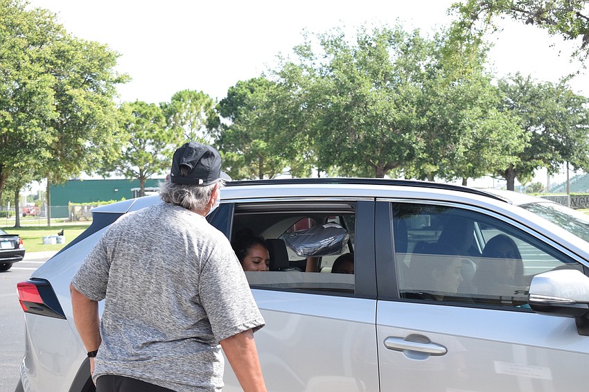 Evelyn Williams, a guidance counselor, hands a cap and gown to senior Jennifer Lopez.