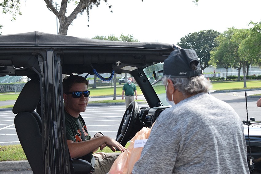 Peyton Miller, a senior, receives his cap and gown from Evelyn Williams, a guidance counselor.