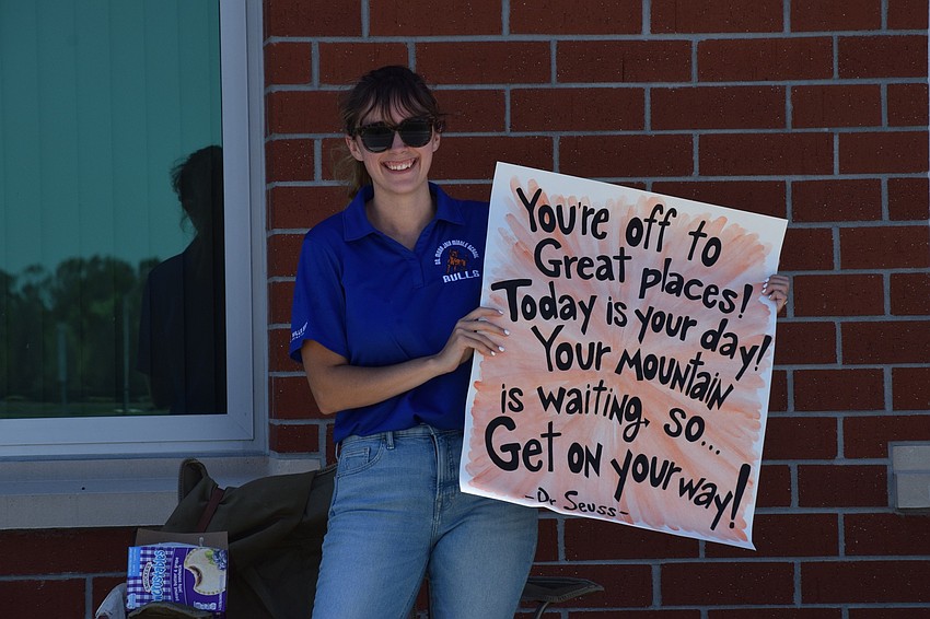 Caitlynn Bonds, an eighth grade language arts teacher, shows off the sign she made for the parade for Mona Jain eighth graders.