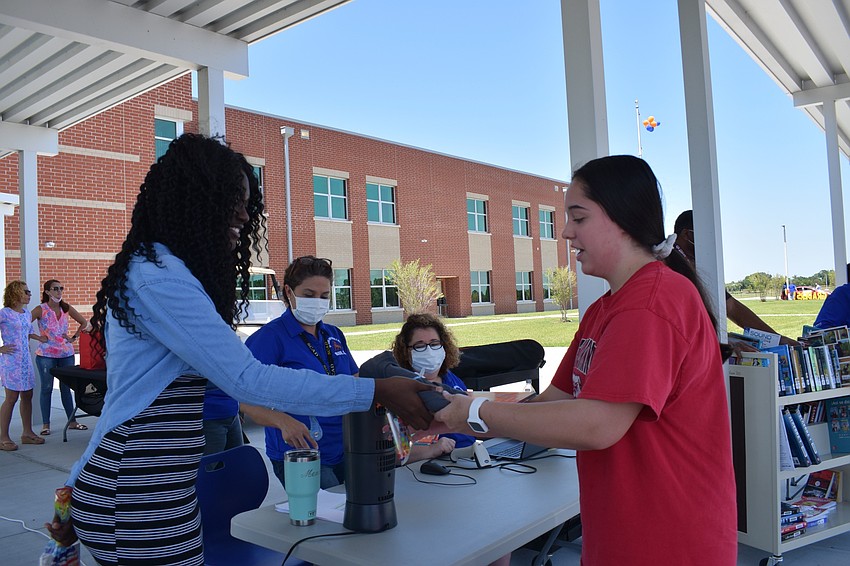 Mona Jain eighth grader Laila Ward hands a gift bag to eighth grader Lauren Wiles.