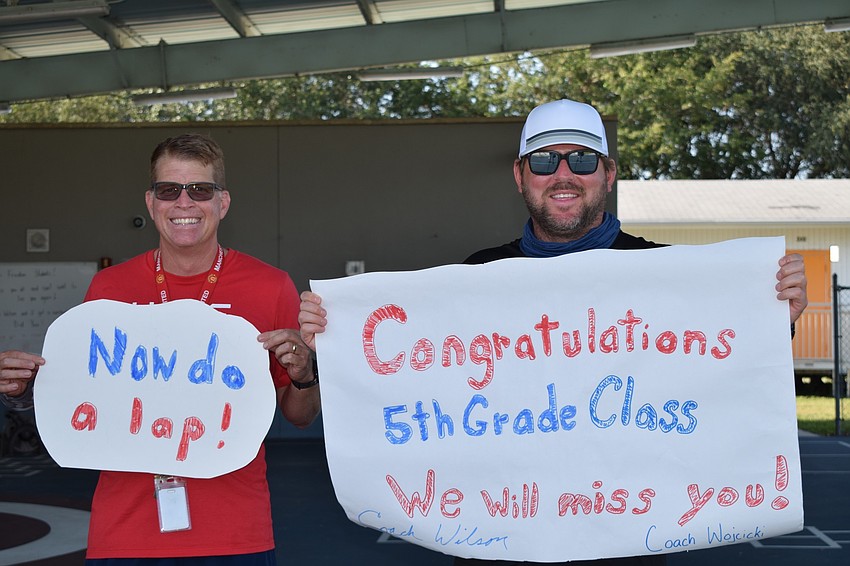 Jeff Wilson and Mark Wojcicki, physical education teachers, get ready to cheer for the fifth graders during a parade.
