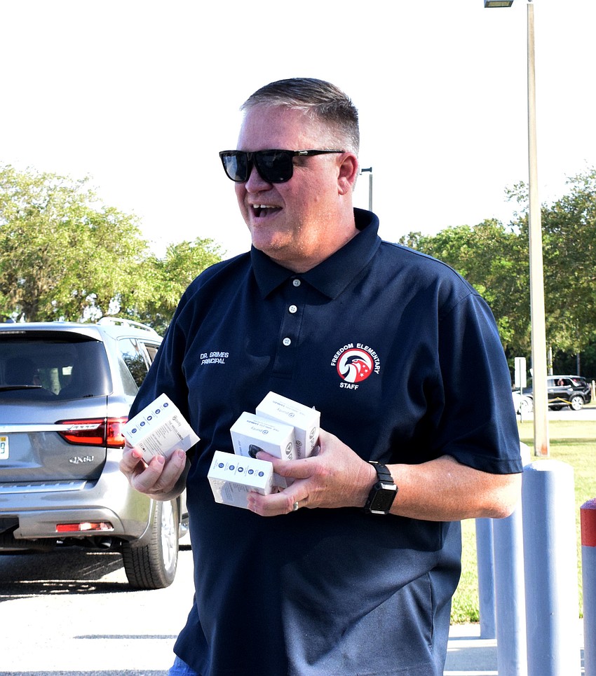 Guy Grimes, principal at Freedom Elementary, hands out wireless headphones to fifth graders as a graduation gift.