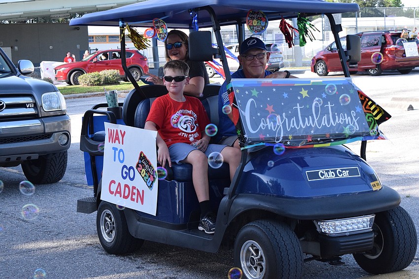 Caden Parker, a Freedom Elementary fifth grader, rides along in a decked out golf cart with his parents Kirsten and Randall Parker.