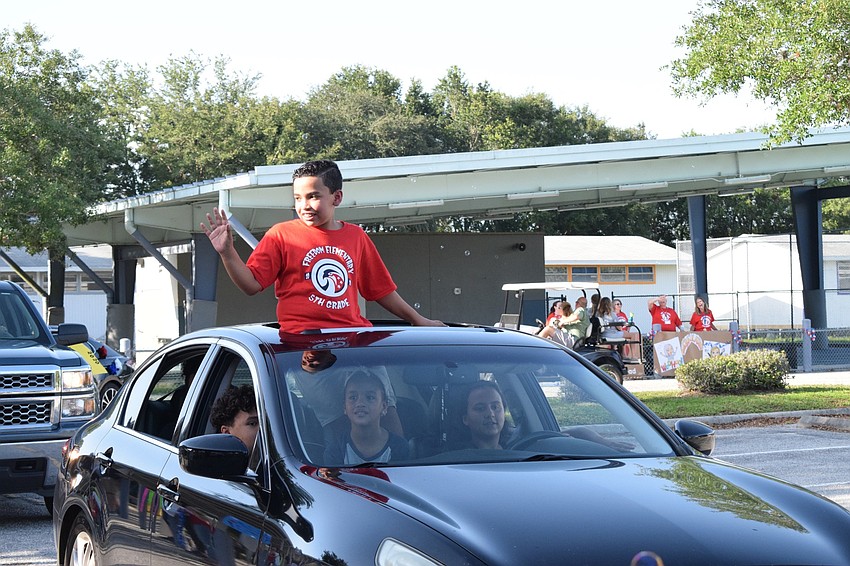 Matias Hernandez-Longart waves to first grade teachers as he nears the end of the parade loop.