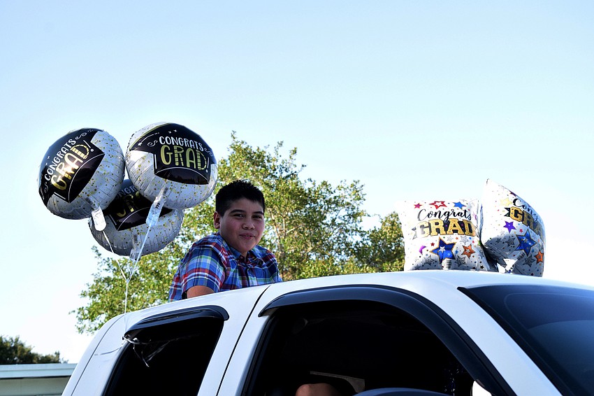 Osiel Sanchez, a fifth grader at Freedom Elementary, celebrates his graduation with balloons tied to his car as he goes through the parade line.