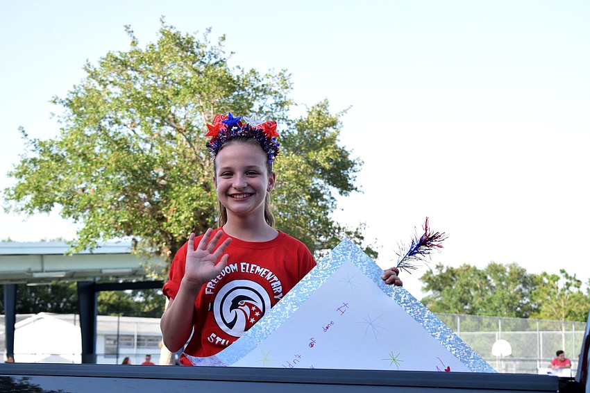 Isabella Colacciao, a Freedom Elementary fifth grader, waves to teachers and staff members during the parade.