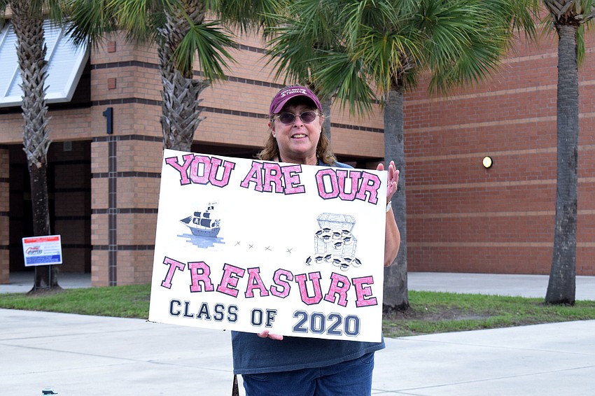 Sheri Wildebour, a paraprofessional, cheers for seniors as they pass by in their cars.