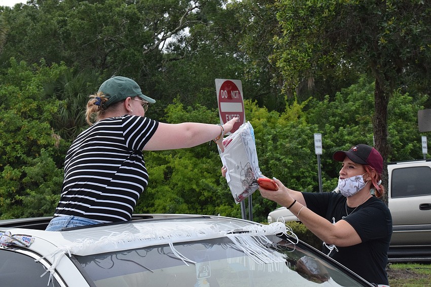 Senior Hannah Badenhorst grabs her cap and gown from Kymmie Marriner, a social studies teacher and a senior advisor.
