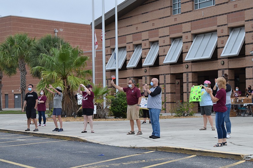 Braden River High School teachers and staff members practice social distancing while cheering for seniors.