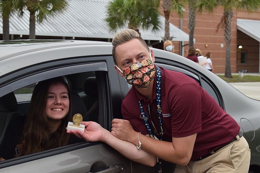 Senior Penelope Sugg receives a trophy from Jeramiah Bowman, the band director.