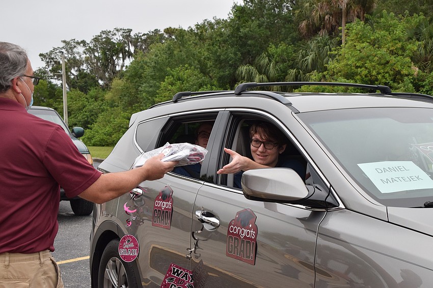 Math teacher Jeff Hill hands senior Daniel Matejek his cap and gown.