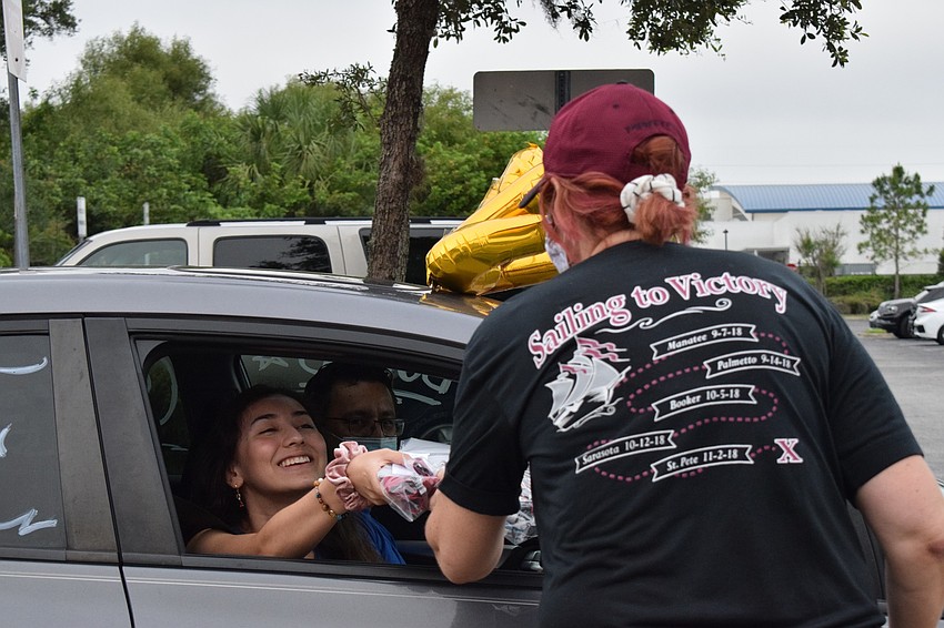 Senior Isabella Macias accepts her cap and gown from Kymmie Marriner, a social studies teacher and senior advisor.