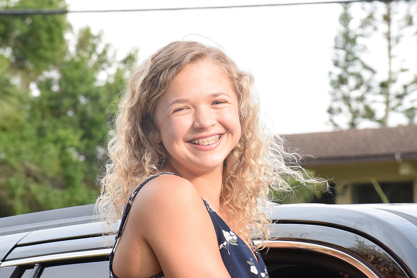 Emmagrace Kelly, an eighth grader, sits outside her car window to see her teachers as she goes through the car loop during the 