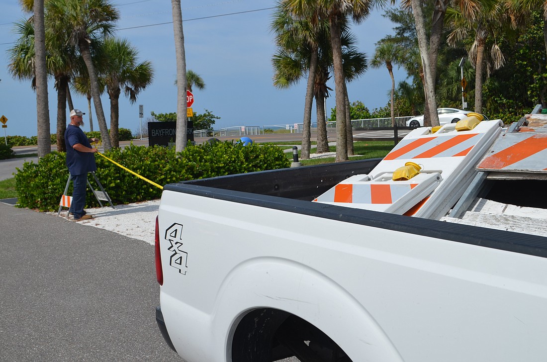 Public Works Department employees roll up tape and haul away barricades that closed off beach parking in Bayfront Park on Monday.
