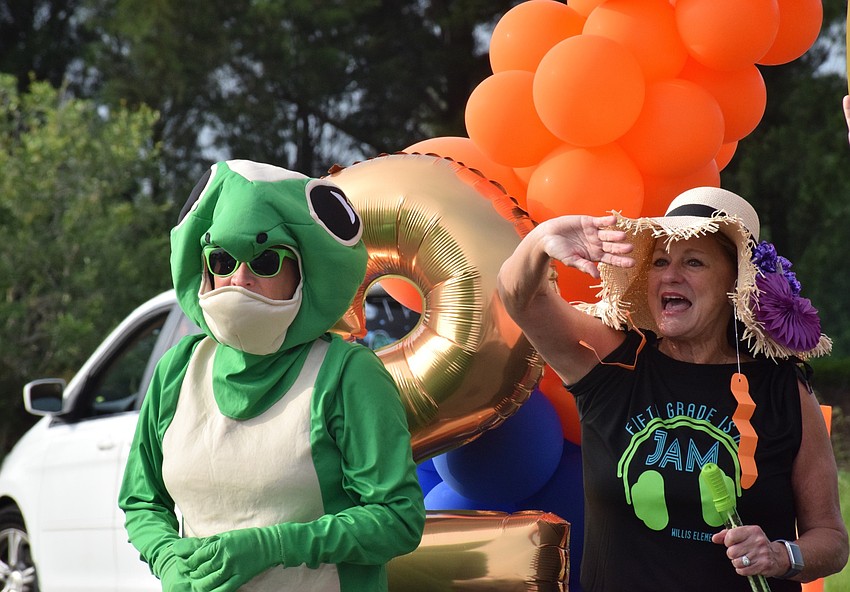 Robert E. Wilis Elementary School's mascot and fifth grade teacher Jacquie McLaurin wave goodbye to students. McLaurin is retiring this year.