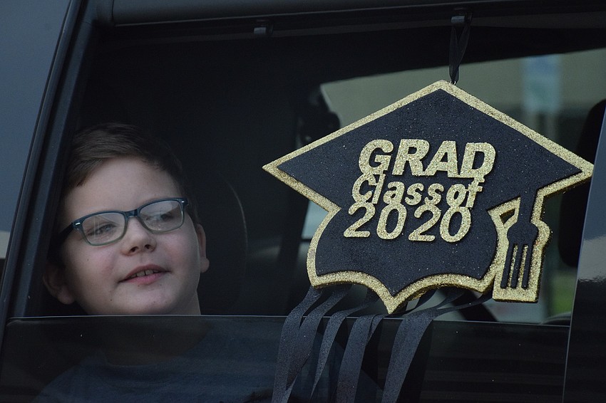 Landon Dickens, a fifth grader at Robert E. Willis Elementary School, peers out his car window to see his teachers.