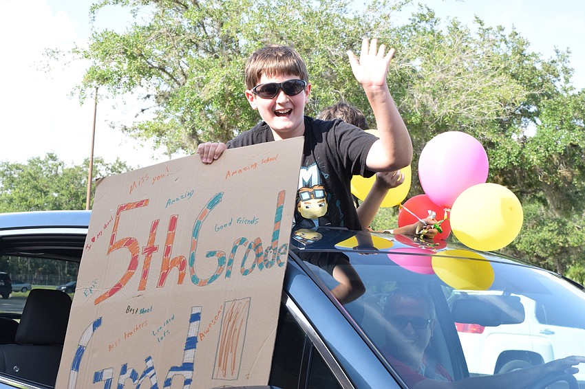 Brady Theison, a fifth grader at Gene Witt Elementary, shows off his handmade sign to teachers as he passes by in the farewell parade.