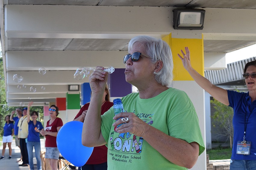 Debbie Pope, a teacher aide at Gene Witt Elementary, blows bubbles at fifth graders as they pass by.
