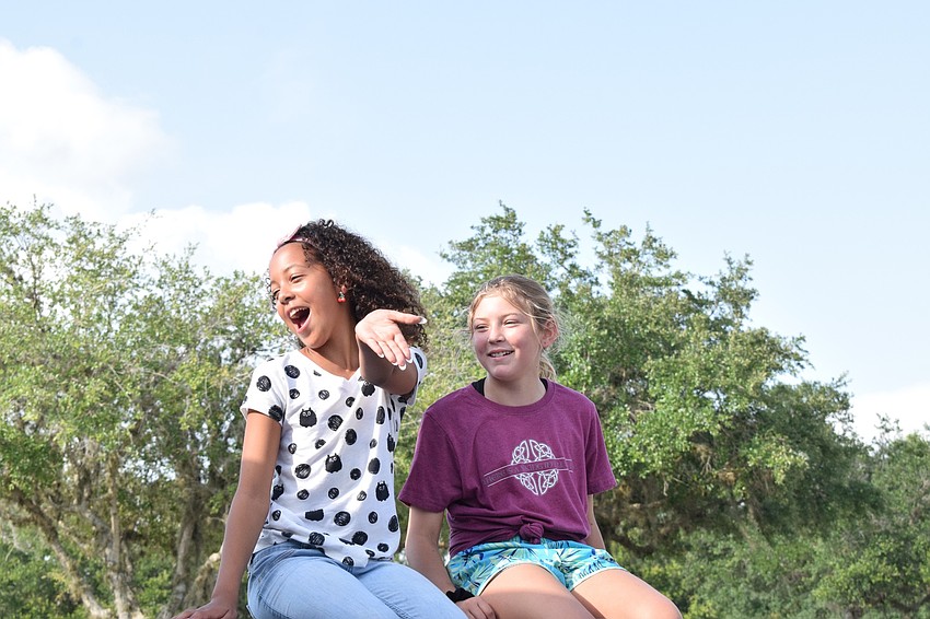 Gene Witt Elementary fifth grader Sienna Lee blows a kiss to her teachers while riding alongside fifth grader Raegan Allian.
