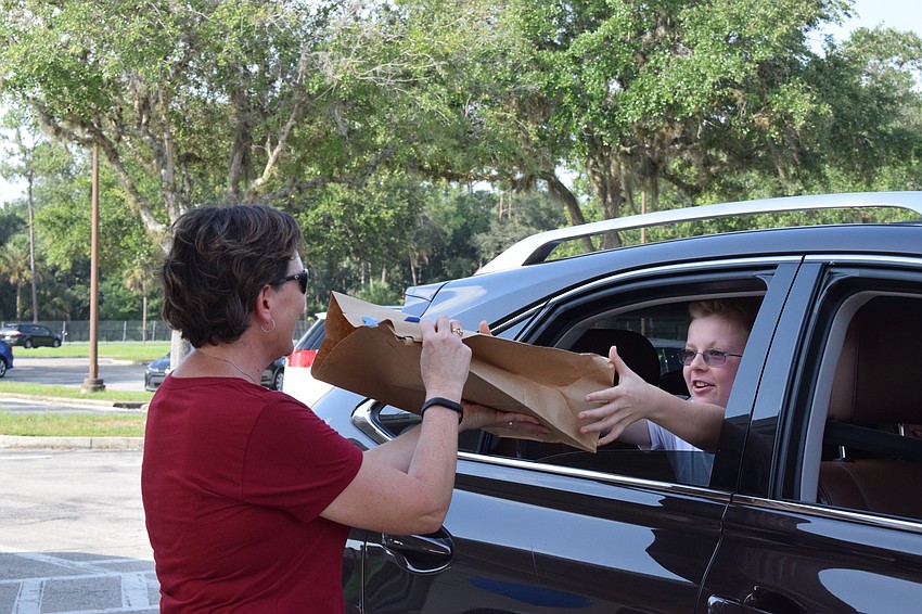 Laura Schuneman, a fifth grade teacher at Gene Witt Elementary School, hands her student Mikolah Zielinski a bag of his belongings he left at school.