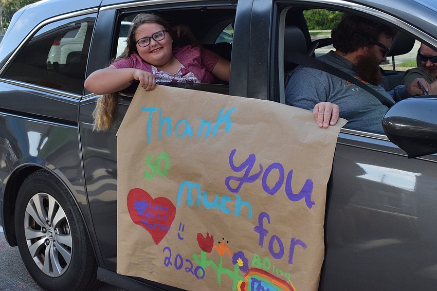 Bella Parker, a fifth grader at Gene Witt Elementary, shows her teachers a homemade sign thanking them for supporting her throughout the school year.