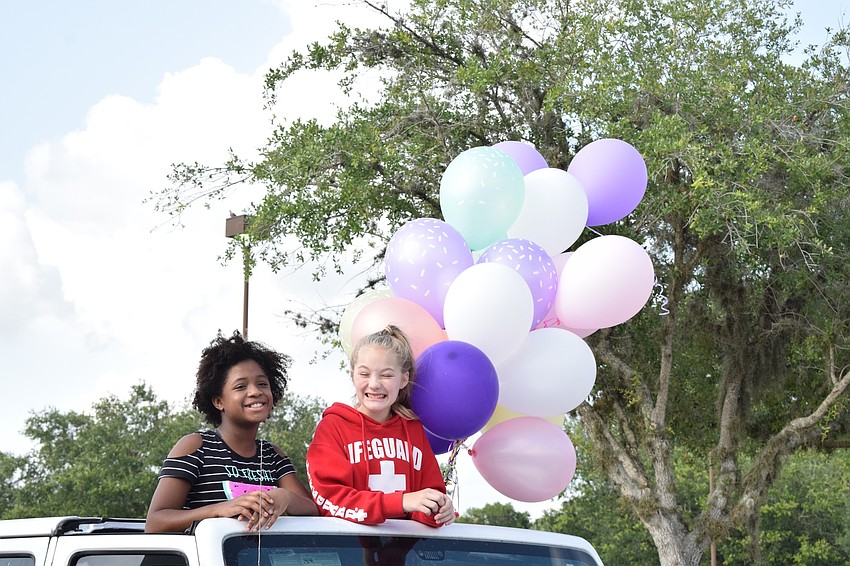 Gene Witt Elementary fifth graders Lauren Everhart and Daphne Dauphas sit on top of a car while going through the school's farewell parade.