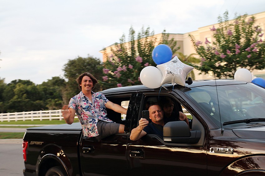 Senior Jarred Flahive leans outside his car window while waving to teachers and staff members. 