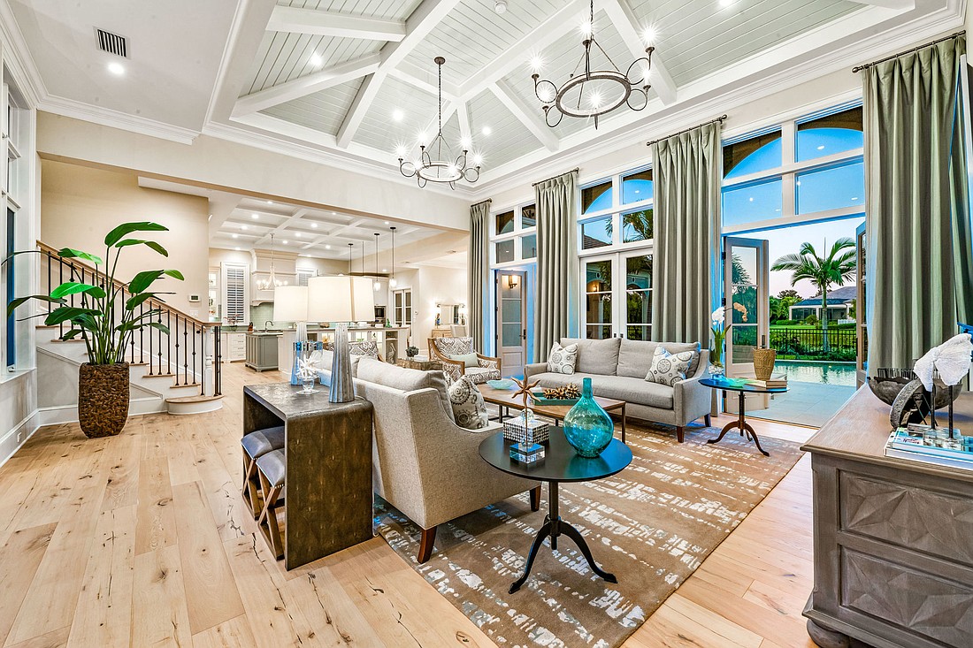 The spacious great room has a coastal feeling, with French doors opening onto the pool area. The stairway at left leads to two guest bedrooms, each with an en suite bath.