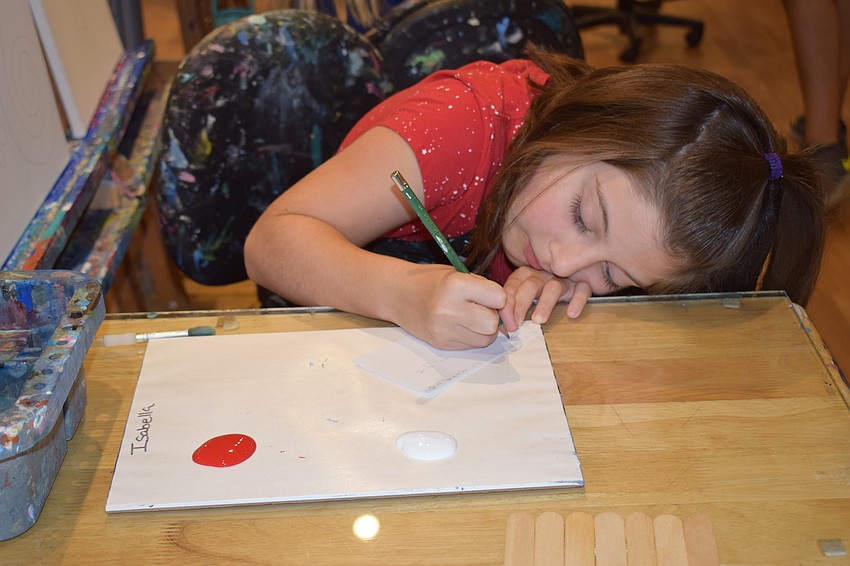 Isabella Brown, 9, of Tampa works to get just the right angle as she paints an art project for her dad, Dan Brown.