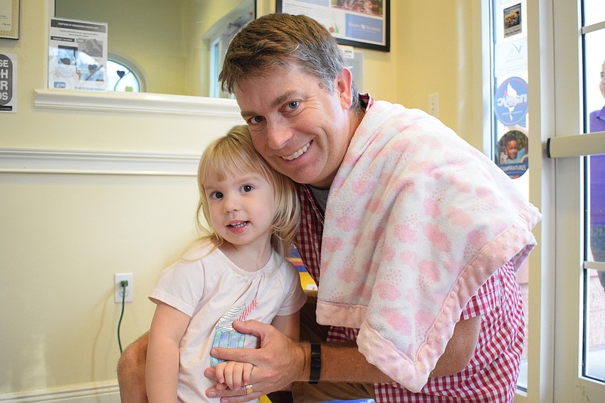 Quinn Warner, a 2-year-old student at Kiddie Academy, gives her dad, Michael, a donut. 