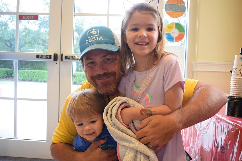 Paul Long hugs his 2-year-old son Logan and 5-year-old daughter Emma before sending them off to class and grabbing coffee and a donut. 