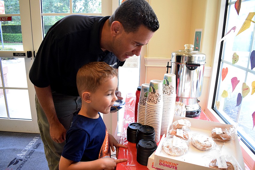 Angel Ortiz and his 4-year-old son Cayden look at the donuts to see their options.