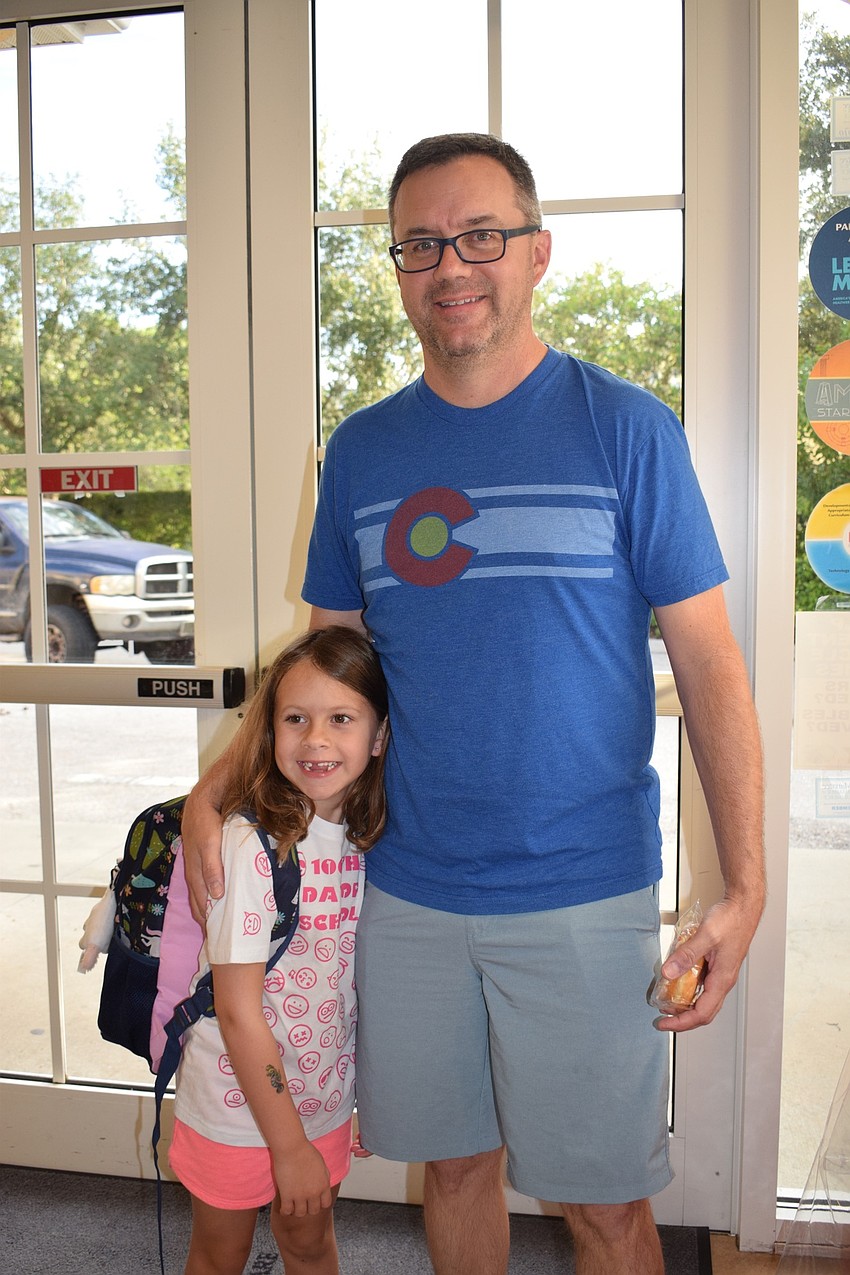 Emma Willard, who is 7, gives her dad, Chuck, a donut as part of Kiddie Academy's Donuts with Dad.