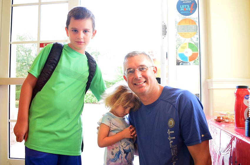 Connor Matthews, 9, and his 3-year-old sister, Emily, give their dad, John, a donut. 