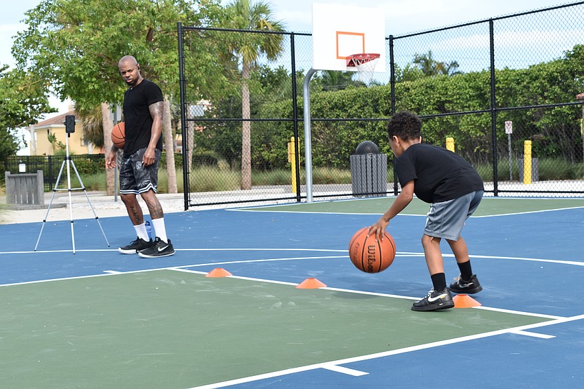 Tim Grant (left) watches his son King Grant (right) perform a dribbling drill.