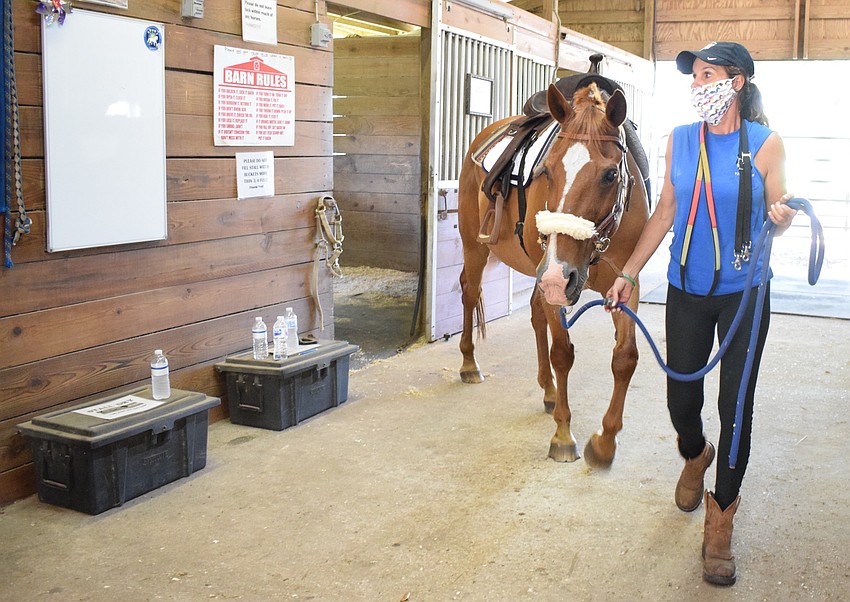 Volunteer Ilee Finochiaro leads Cherokee out to the arena. Sarasota-Manatee Association for Riding Therapy has at least five volunteers to work with five campers.