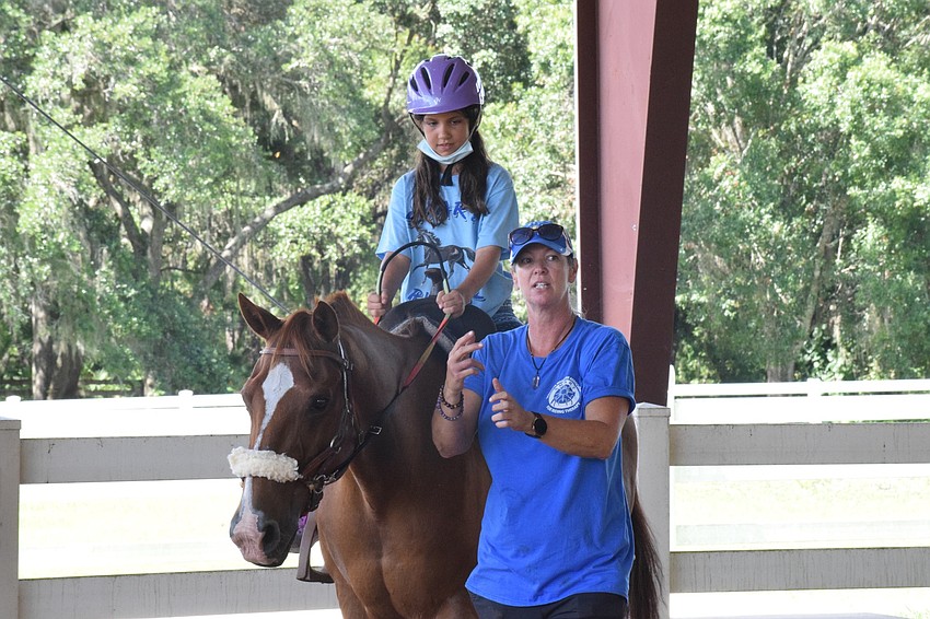Camper Lilly Gerling, who is 9, listens to equine manager Samantha Toomey while she rides Cherokee. Cherokee is 22 years old.