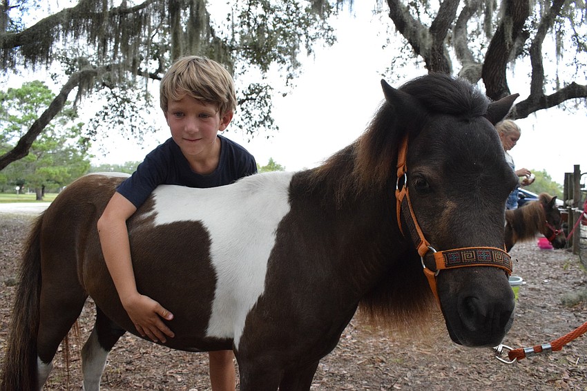Mateo Murariu, a 6-year-old camper, hugs his horse, Rowdy, while explaining how to groom him. 