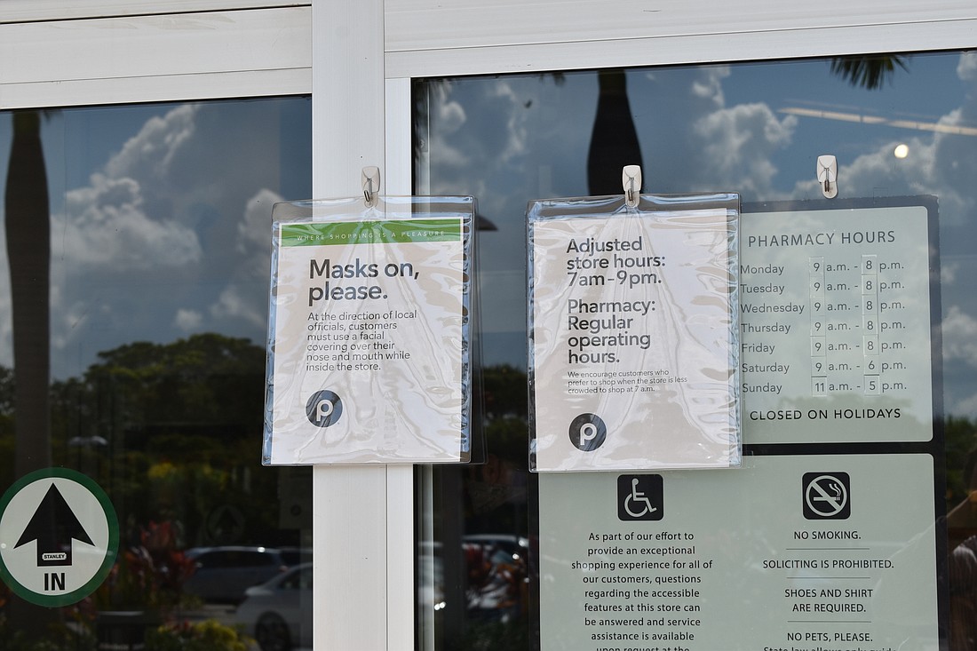Signage outside of Publix requires most customers to wear a mask upon entering the store.