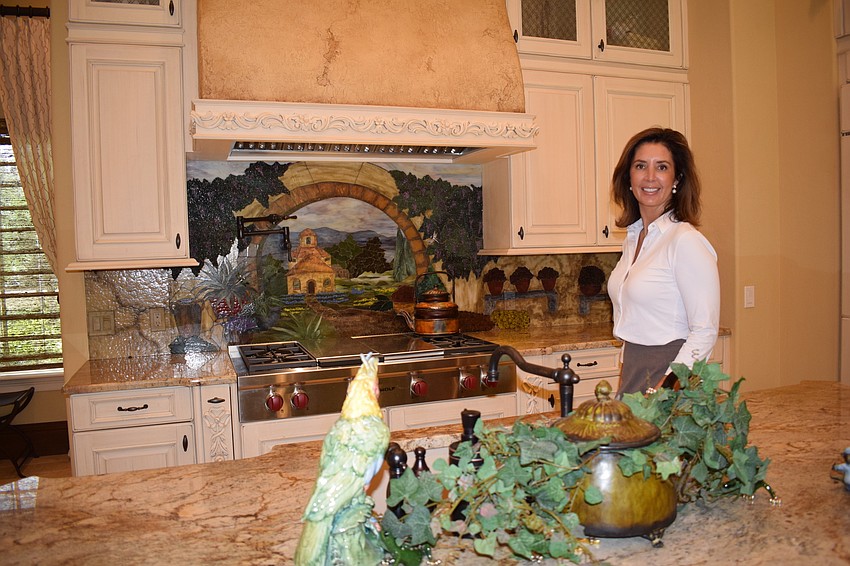 Realtor Laura Stavola of the Soda-Stavola Group shows off the artwork in the kitchen. Photo by Jay Heater